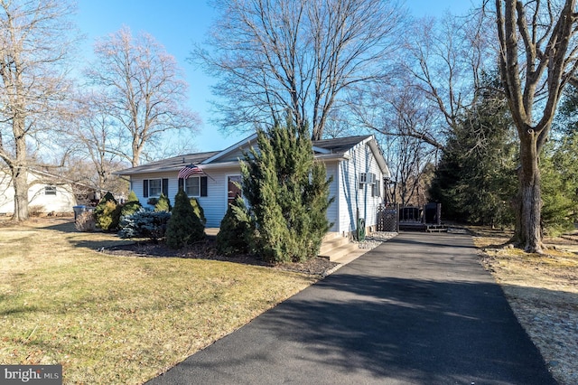 view of property exterior with aphalt driveway and a lawn