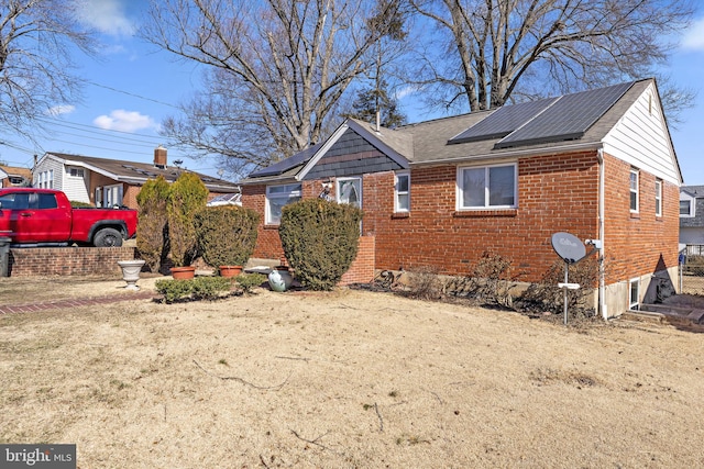 view of front of house featuring brick siding and roof mounted solar panels