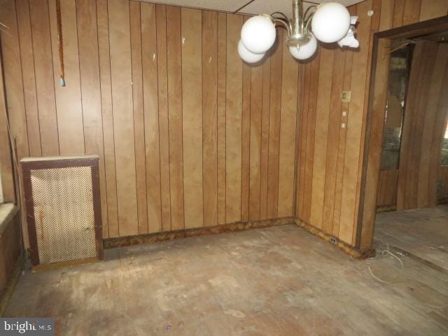 unfurnished room featuring a chandelier and wooden walls