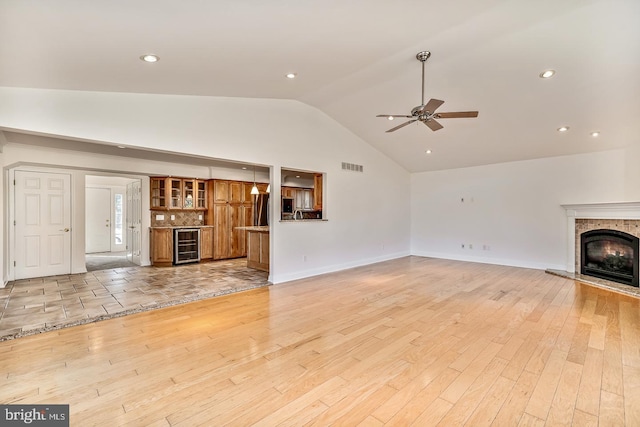 unfurnished living room featuring ceiling fan, high vaulted ceiling, wine cooler, and light hardwood / wood-style floors