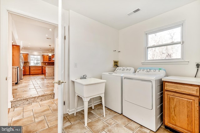 clothes washing area featuring cabinets and washer and clothes dryer