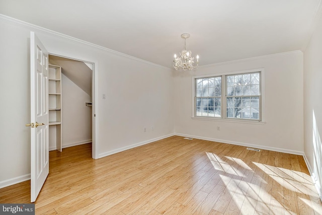 spare room featuring ornamental molding, light hardwood / wood-style floors, and a chandelier