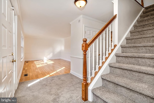 staircase featuring crown molding and wood-type flooring