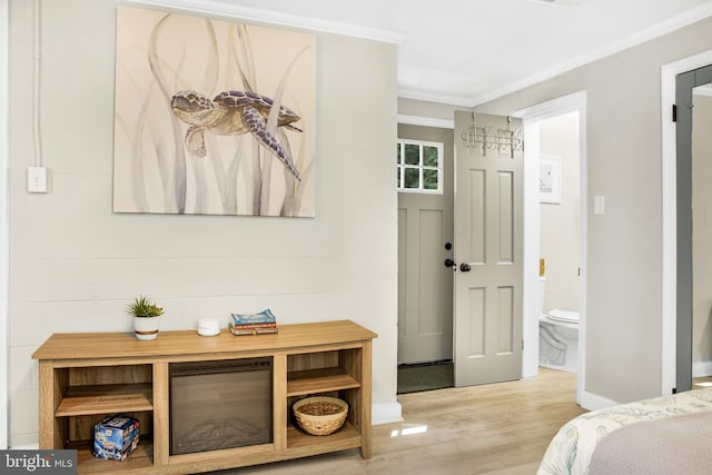 bedroom featuring crown molding, connected bathroom, and light wood-type flooring