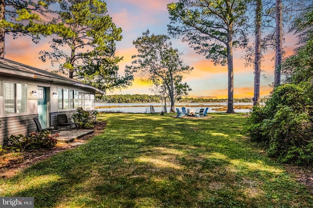 yard at dusk with a patio and a water view