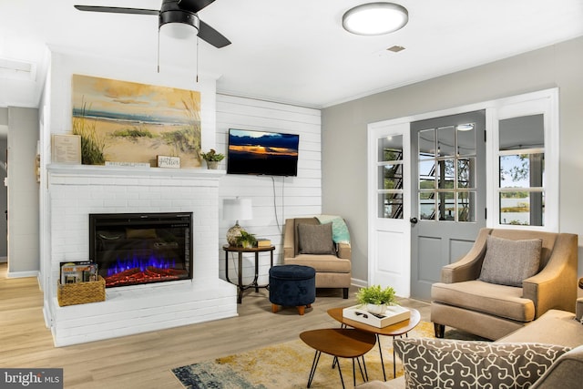 living room featuring ceiling fan, a fireplace, and light hardwood / wood-style floors