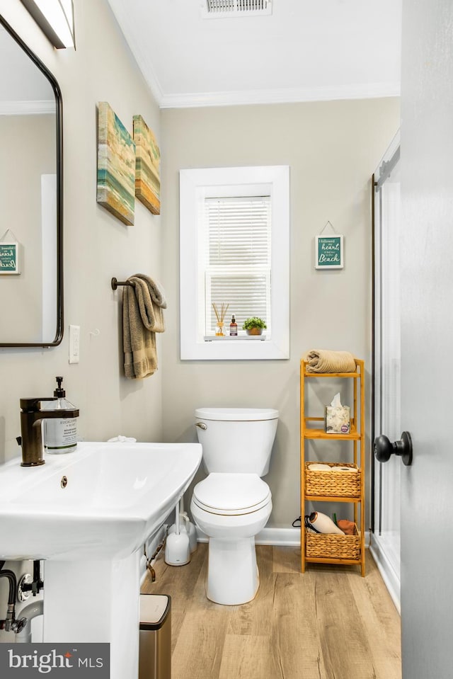 bathroom featuring wood-type flooring, ornamental molding, and toilet