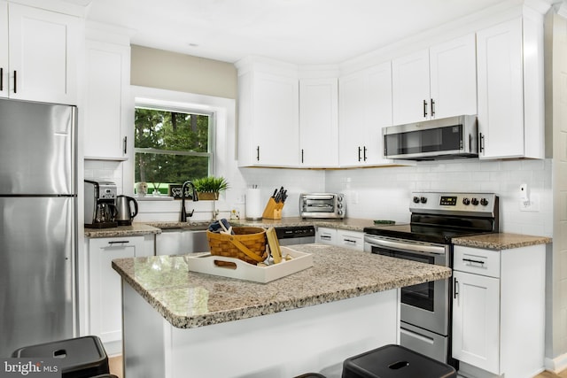 kitchen with stainless steel appliances, white cabinetry, sink, and backsplash