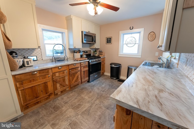 kitchen with sink, ceiling fan, white cabinetry, backsplash, and stainless steel appliances