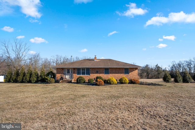 view of front of property featuring brick siding, a chimney, and a front lawn