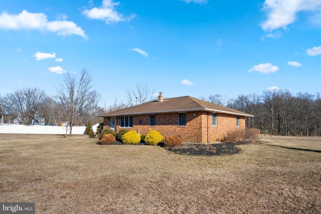 view of side of home with a yard, brick siding, and a chimney