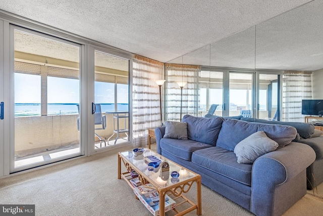 living room featuring expansive windows, a water view, carpet floors, and a textured ceiling