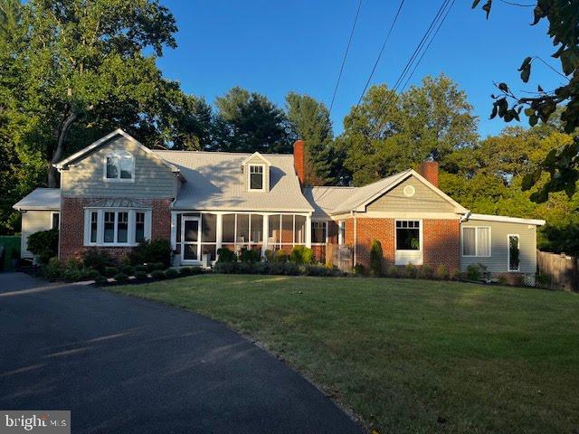 view of front of home featuring a front yard, a sunroom, and brick siding