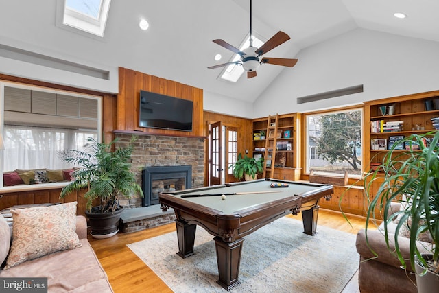 playroom with light wood finished floors, a fireplace, a skylight, and a healthy amount of sunlight