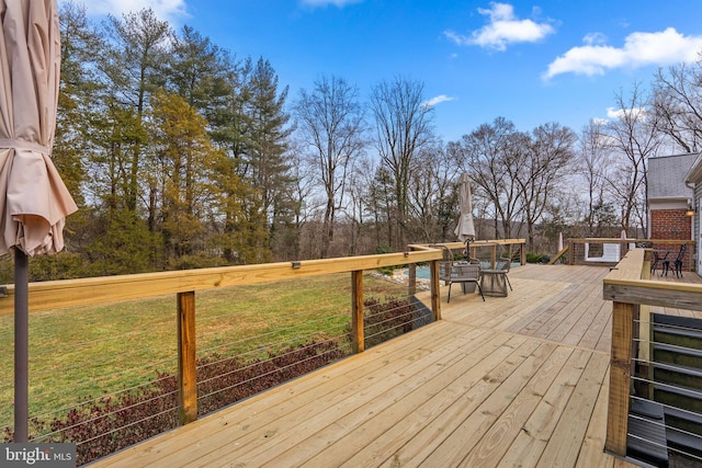 deck featuring outdoor dining area and a lawn