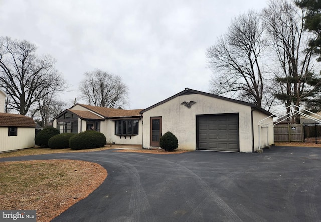 single story home featuring driveway, an attached garage, fence, and stucco siding