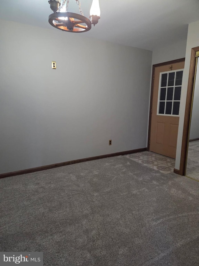 empty room with baseboards, a chandelier, and dark colored carpet