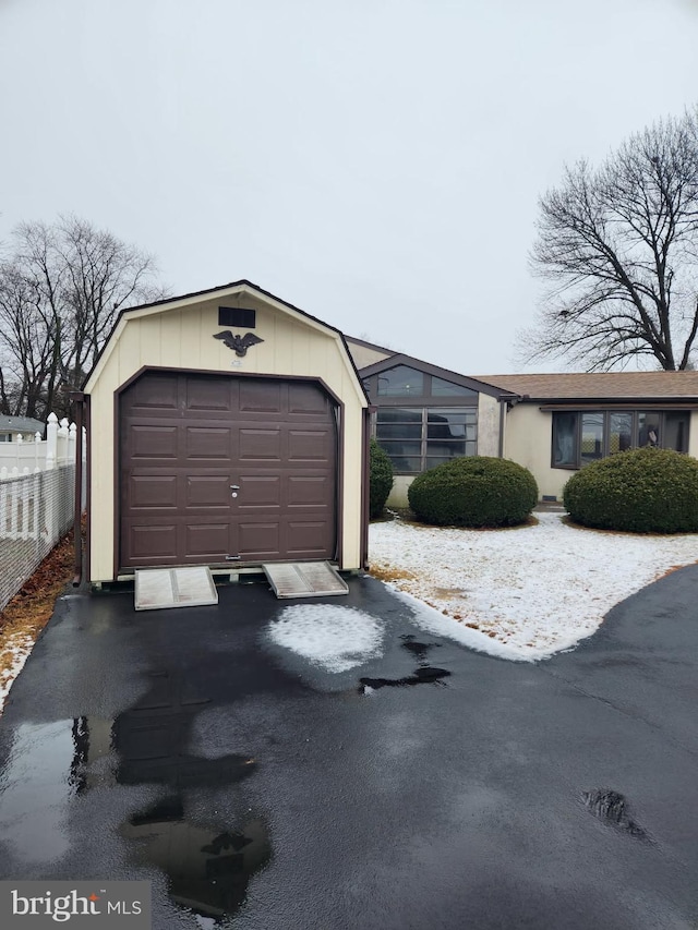 detached garage featuring driveway and fence