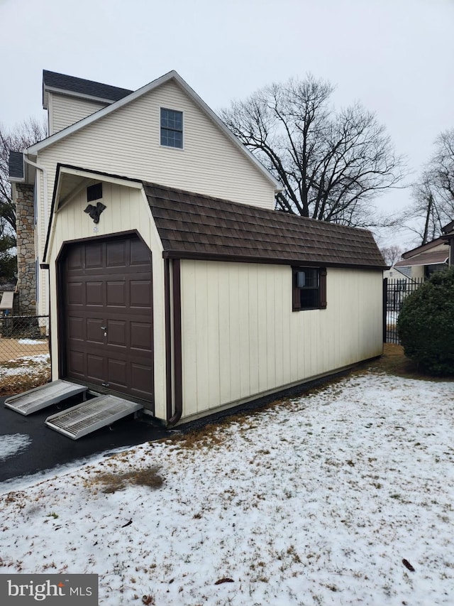 snow covered garage with fence