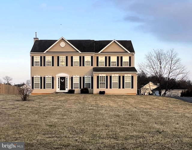 colonial home with a front yard and fence