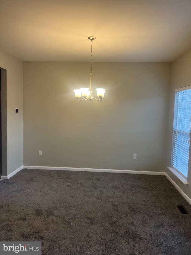 unfurnished room with visible vents, baseboards, an inviting chandelier, and dark carpet