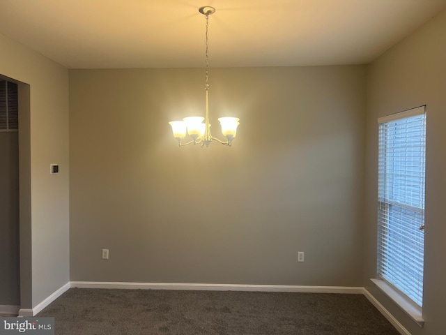 empty room with dark colored carpet, baseboards, and an inviting chandelier