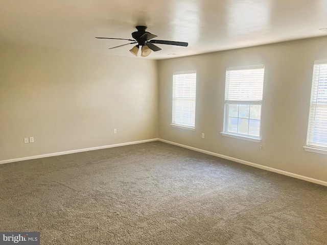 spare room featuring baseboards, ceiling fan, and dark colored carpet