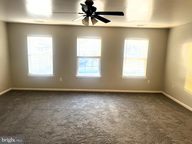 spare room with plenty of natural light, baseboards, and dark carpet