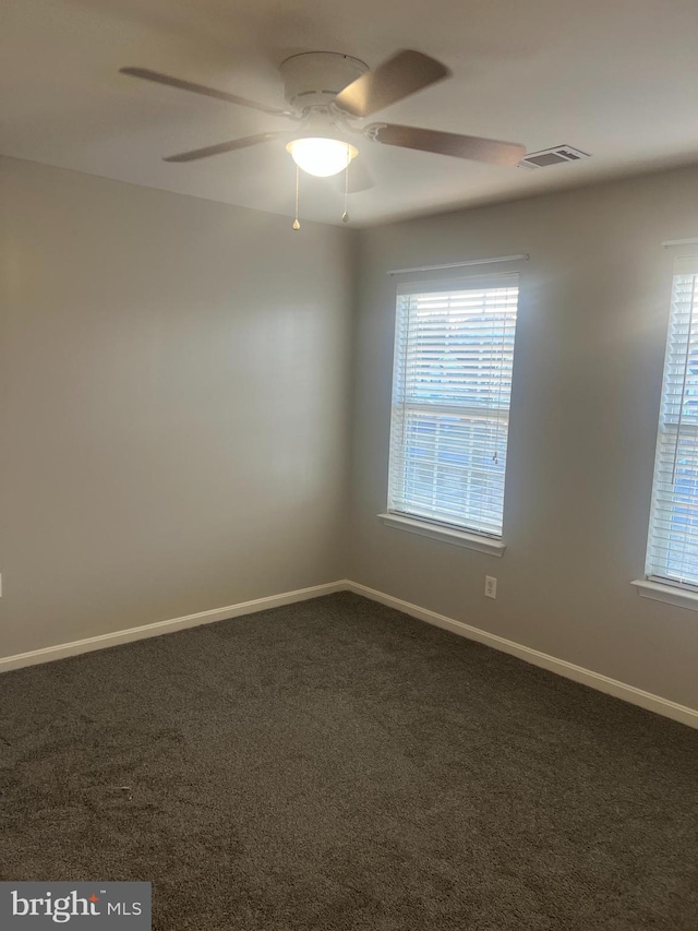 carpeted spare room featuring visible vents, baseboards, a healthy amount of sunlight, and ceiling fan