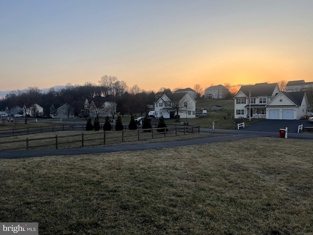 view of property's community featuring fence, a residential view, a garage, a yard, and driveway