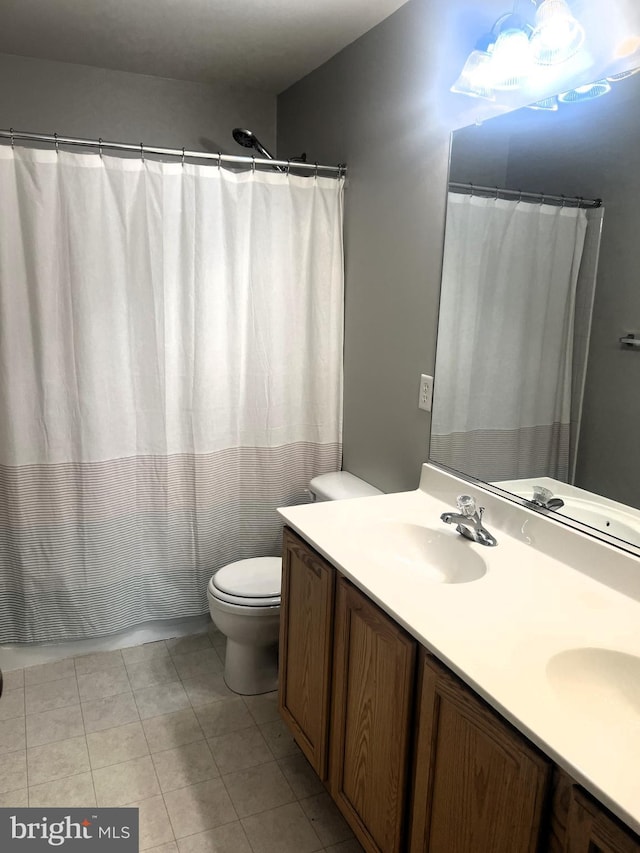 full bath with double vanity, tile patterned floors, toilet, and a sink