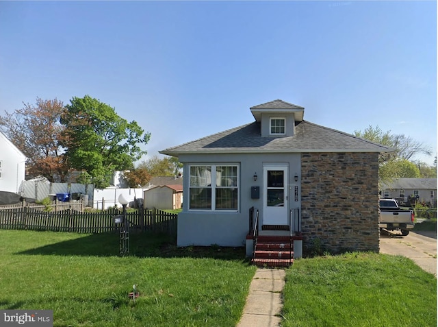 bungalow-style house featuring stucco siding, a shingled roof, fence, and a front yard