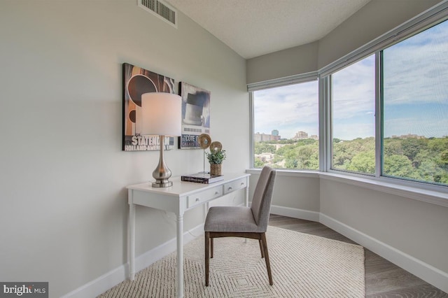 office with visible vents, a textured ceiling, baseboards, and wood finished floors