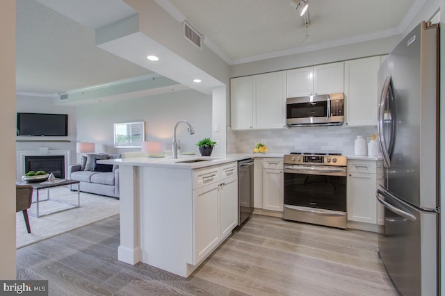 kitchen with open floor plan, stainless steel appliances, light countertops, and white cabinets