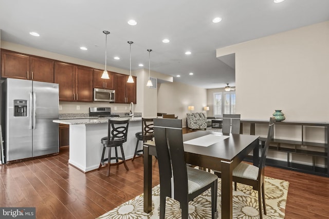 dining space featuring sink, dark wood-type flooring, and ceiling fan