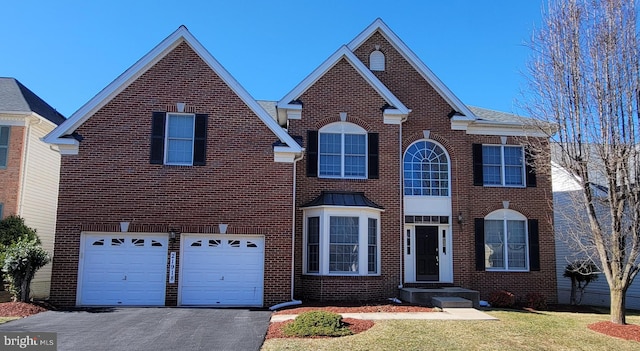 view of front of house with driveway, an attached garage, a front yard, and brick siding