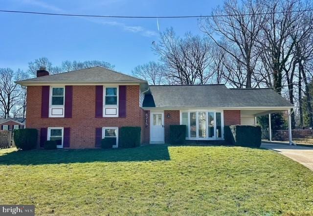 tri-level home with driveway, a chimney, a front lawn, and a carport