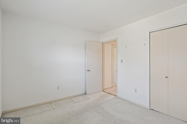 unfurnished bedroom featuring carpet floors, a closet, and baseboards