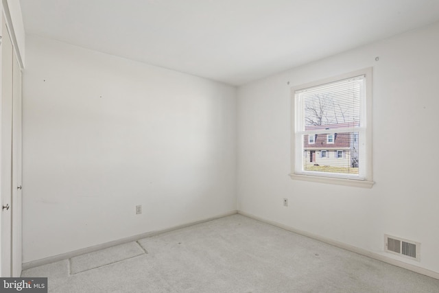 carpeted spare room featuring baseboards and visible vents