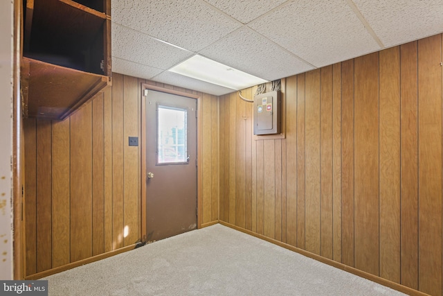 interior space featuring carpet floors, a paneled ceiling, electric panel, and wooden walls