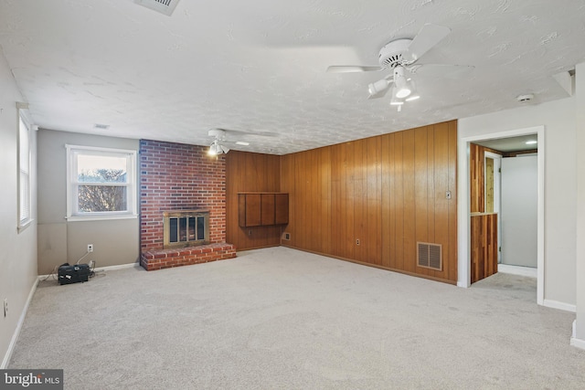 unfurnished living room with wooden walls, carpet, a fireplace, and visible vents