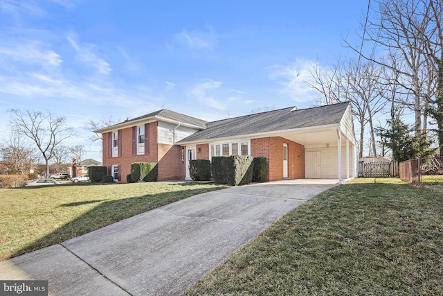 tri-level home with an attached carport, brick siding, fence, concrete driveway, and a front lawn