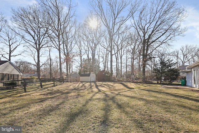 view of yard featuring a storage shed, an outdoor structure, and fence