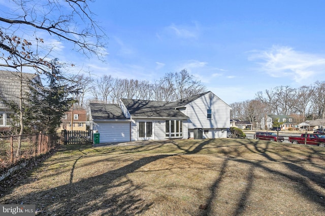 rear view of house featuring a yard and fence