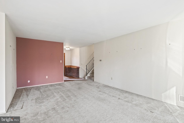 spare room featuring stairs, carpet flooring, and visible vents