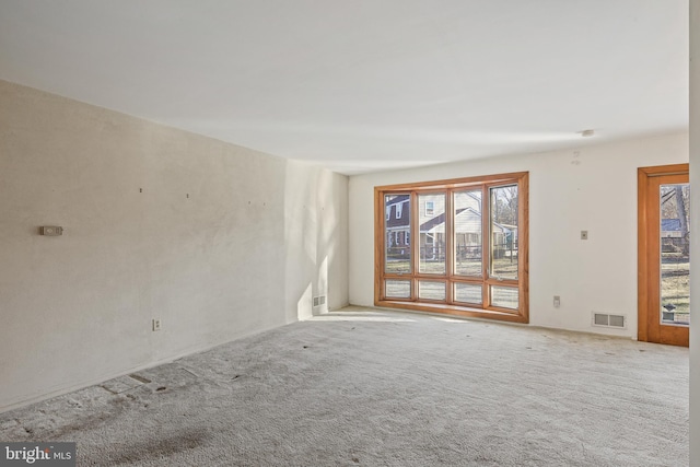 carpeted empty room featuring visible vents