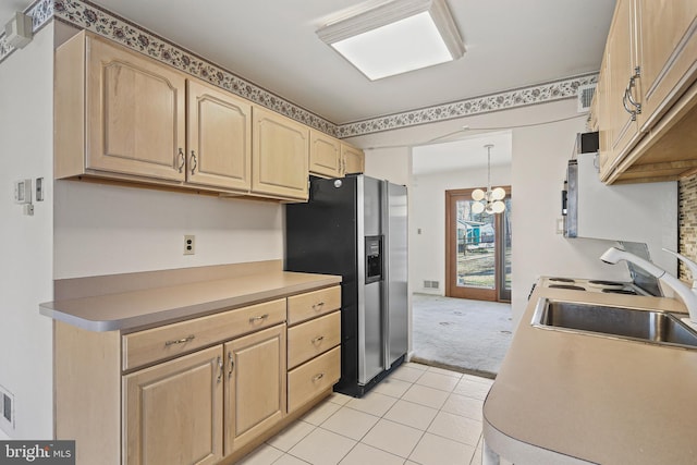 kitchen featuring light tile patterned floors, light colored carpet, light brown cabinetry, a sink, and stainless steel fridge with ice dispenser