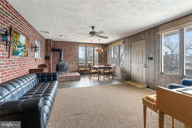 carpeted living room featuring a wood stove, a wealth of natural light, and a textured ceiling