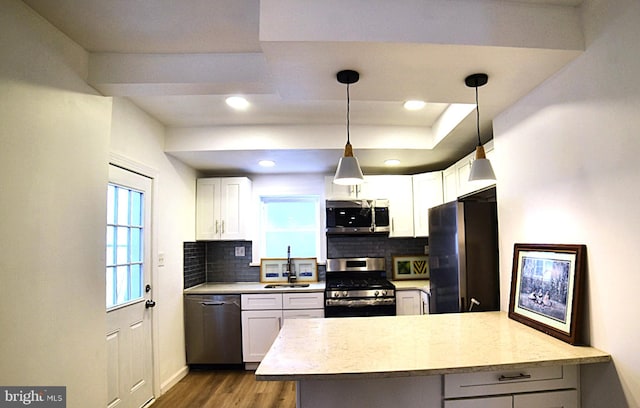 kitchen featuring sink, white cabinetry, stainless steel appliances, decorative light fixtures, and kitchen peninsula