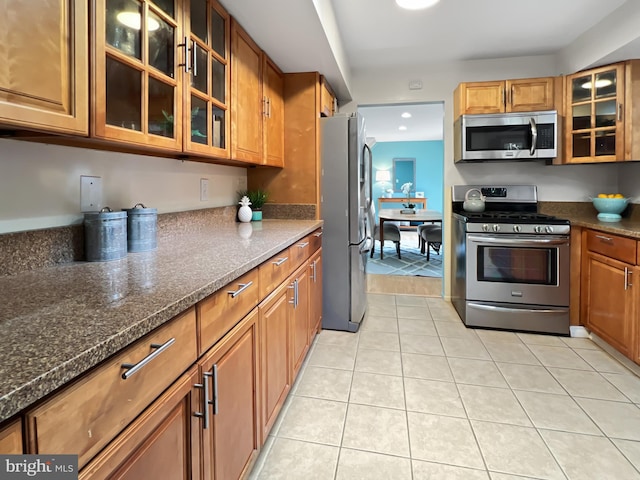 kitchen featuring stainless steel appliances, glass insert cabinets, and brown cabinets